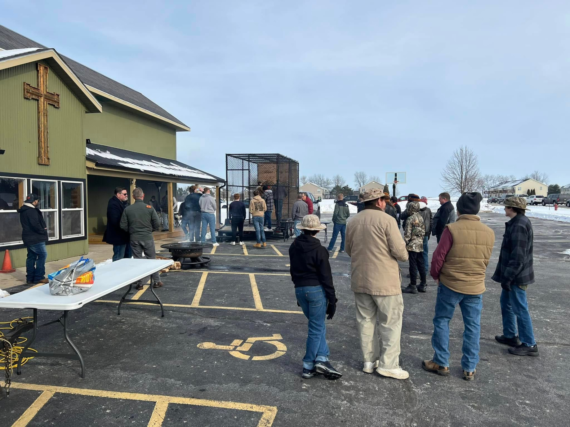 Men gathered outside around a fire pit on a winter morning